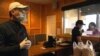 Staffers wear surgical masks and gloves as they prepare food for a customer through the to-go window at Thai House Restaurant in Gaithersburg, MD., March 29, 2020. 