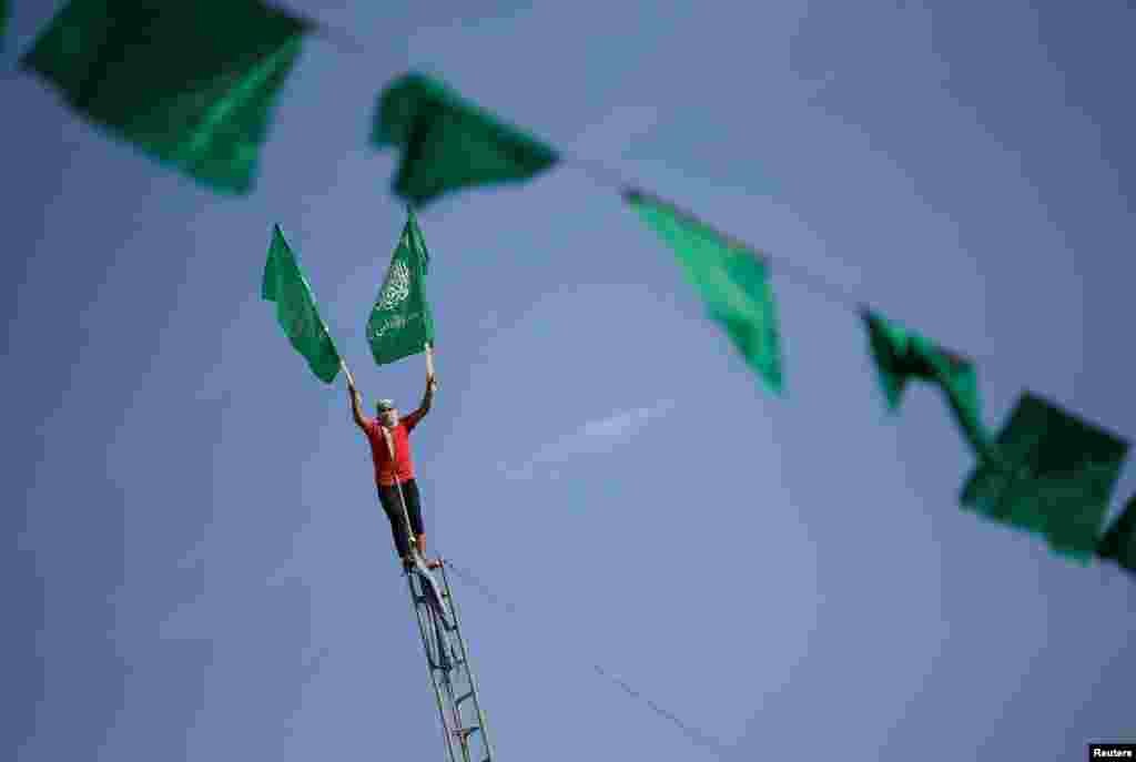 Bunting hangs as a Palestinian holds flags on a ladder at a rally marking the 34th anniversary of Hamas' founding, in the northern Gaza Strip.