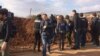 Reporters hurry up what looks to be a berm with views of mountainsides controlled by apposing militaries on Feb. 1, 2018 in Marin, Syria. (H.Murdock/VOA)