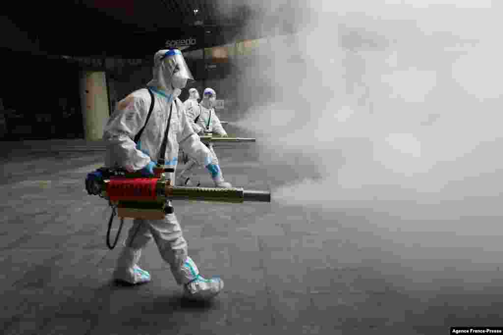 Staff members wearing personal protective equipment (PPE) spray disinfectant outside a shopping mall in Xi'an in north China's Shaanxi province.