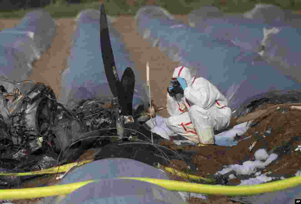 A person investigates the debris of a small plane at an asparagus field in the village Erzhausen near Frankfurt, Germany. Russian airline S7 Group said co-owner Natalia Fileva was aboard the single-engine, six-seat Epic LT aircraft that crashed and burned on March 31, 2019, in a field as it approached the small airport at Egelsbach near Frankfurt.