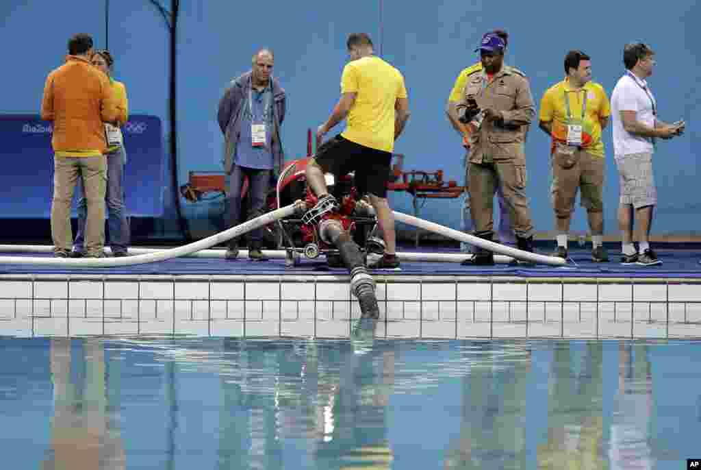 Technical officers and staff members of the Lenk Aquatic Center watch as the process of draining the pool where the 2016 Summer Olympics synchronized swimming competition is to be held in Rio de Janeiro, Brazil, started Aug. 13, 2016.
