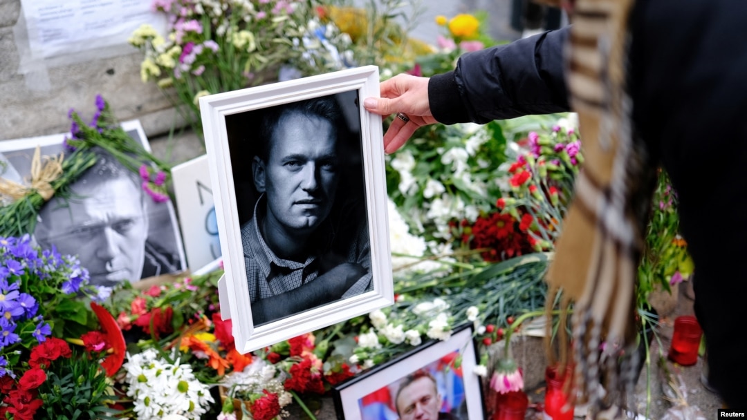 A woman places a portrait of late Russian opposition leader Alexey Navalny, who died unexpectedly in prison, on his memorial at Las Ramblas of Barcelona, in Barcelona, Spain, Feb. 25, 2024.