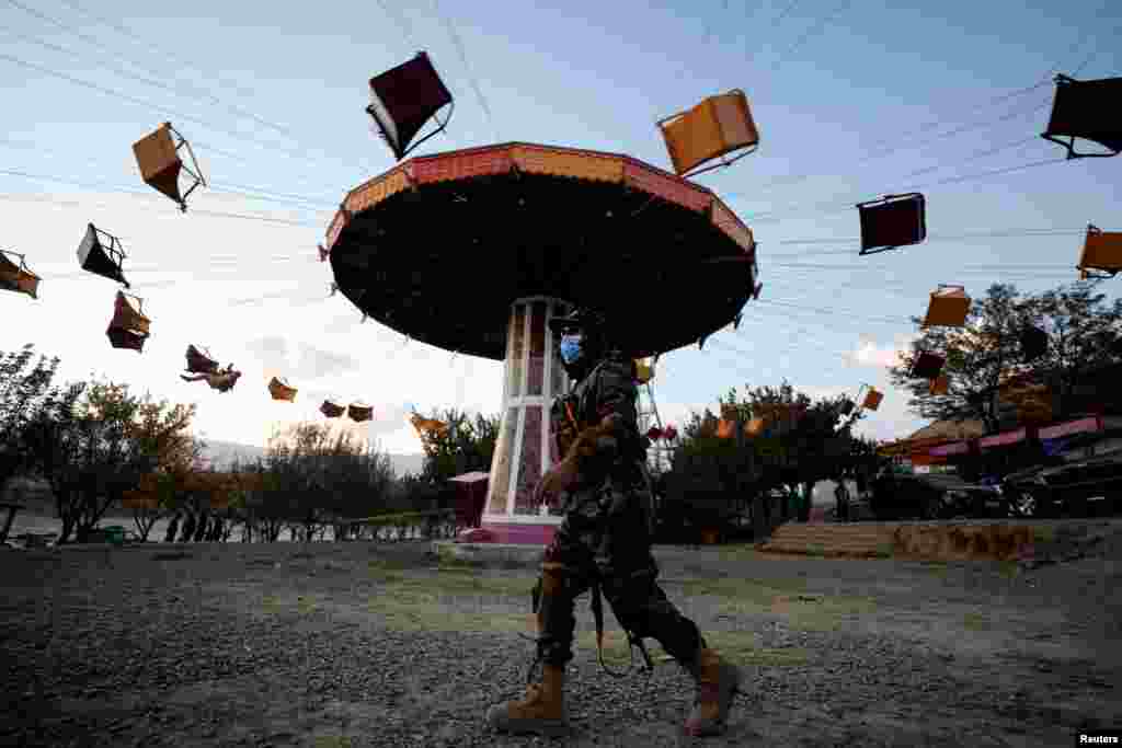 A Taliban fighter walks past a ride as he takes a day off to visit the amusement park at Kabul's Qargha reservoir in the outskirts of Kabul, Afghanistan Oct. 29, 2021.