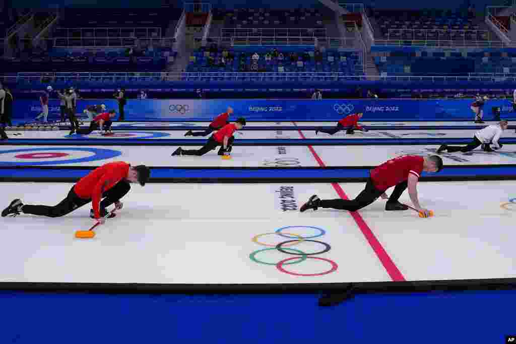 Men's teams warm up before their curling matches, at the 2022 Winter Olympics, in Beijing.