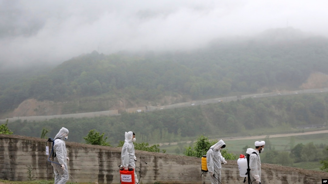 FILE - Volunteers wearing protective clothing, take part in disinfecting a village during the coronavirus outbreak, in the outskirts of the city of Ghaemshahr, in north of Iran, April 29, 2020.