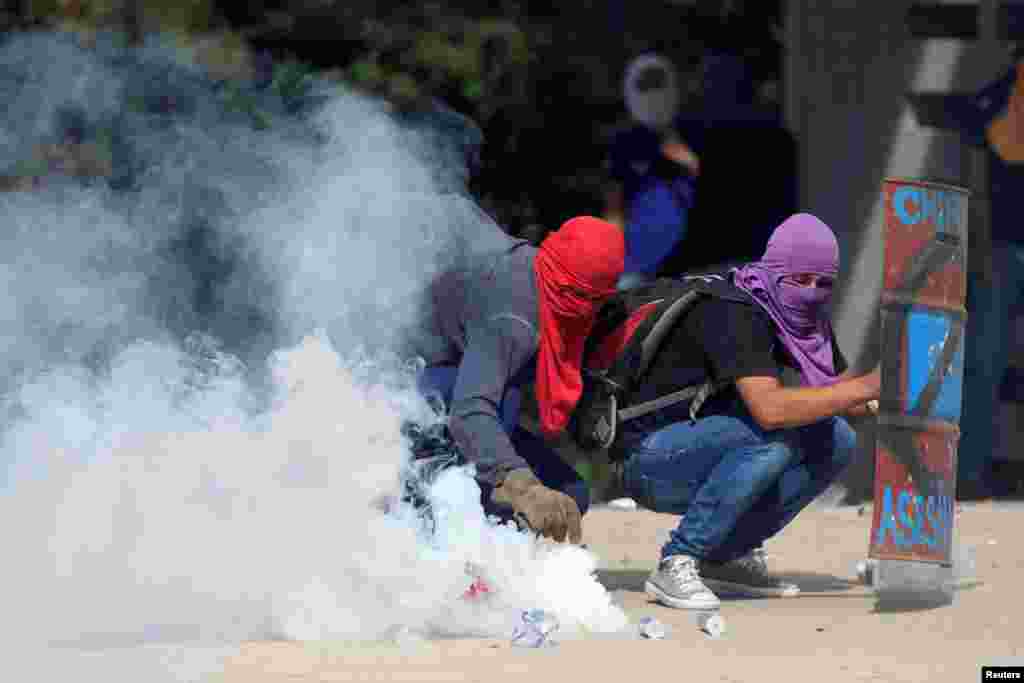 A demonstrator holds a tear gas canister fired by policemen during a protest against the government of President Juan Orlando Hernandez outside the National Autonomous University of Honduras (UNAH) in Tegucigalpa, Honduras, Nov. 28, 2018.