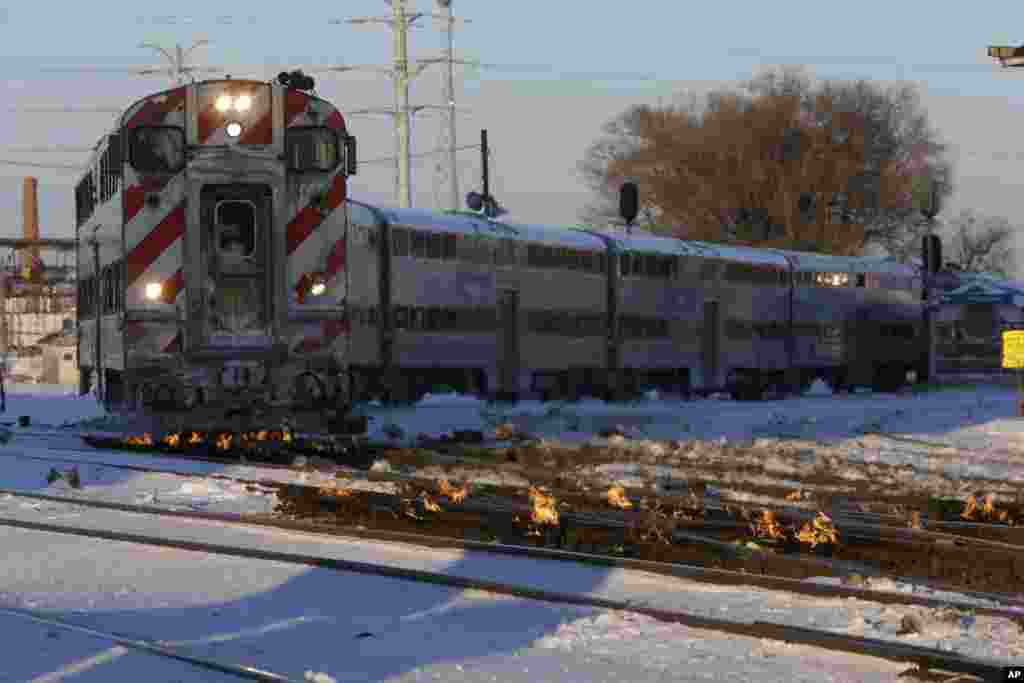 A Metra train moves southbound to downtown Chicago as the gas-fired switch heater on the rails keeps the ice and snow off the switches near Metra Western Avenue station in Chicago, Illinois. Forecasters warn that the freezing weather will get worse and could be life-threatening.