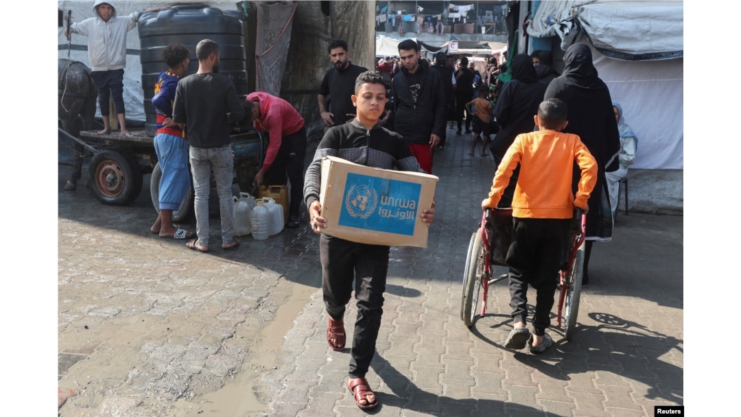 FILE - A Palestinian carries an aid box distributed by the U.N. Relief and Works Agency (UNRWA), amid the Israel-Hamas conflict, in Deir al-Balah, central Gaza Strip, Nov. 4, 2024.