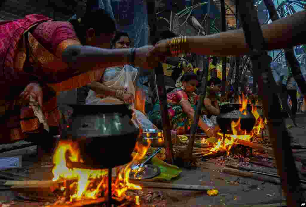 Tamil women greet each other as they cook special food to celebrate the harvest festival of Pongal at Dharavi, one of the Asia's largest slums, in Mumbai, India.