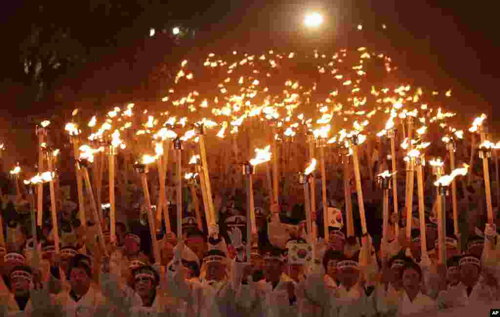 Participants carry torches and national flags as they march on the street during a re-enactment ceremony of the March First Independence Movement Day, the anniversary of the 1919 uprising against Japanese colonial rule, in Cheonan, South Korea.
