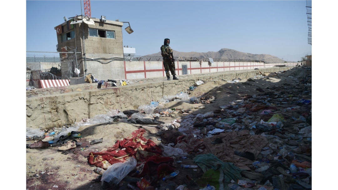 A Taliban fighter stands guard at the site of the Aug. 26 suicide bombing, which killed scores of people including 13 US troops, at Kabul airport on Aug. 27, 2021.