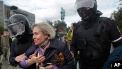 Police officers detain a woman during an unsanctioned rally in the center of Moscow, Russia, Saturday, Aug. 3, 2019.