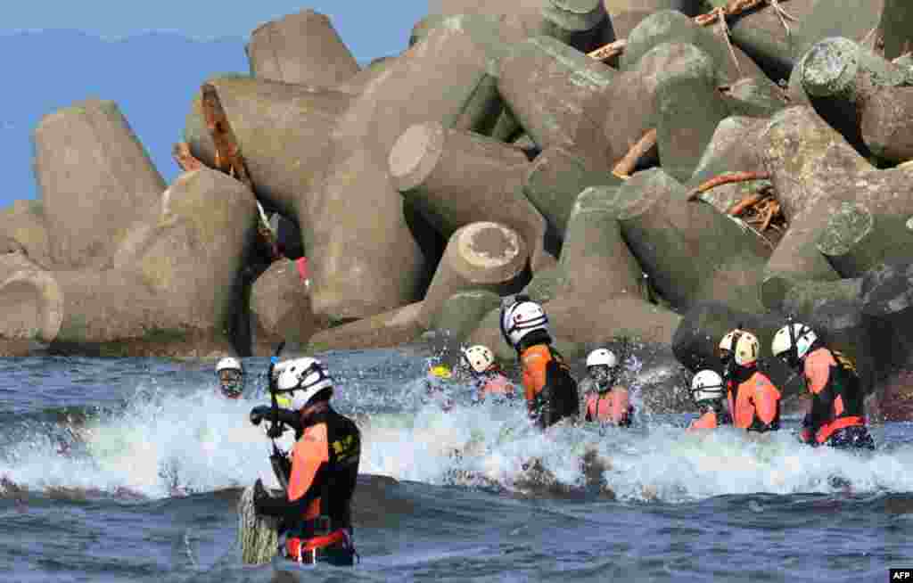A Japanese Coast Guard marine rescue unit searches for missing persons off Oshima island, 120 km south of Tokyo. A painstaking search through tons of mud and splintered houses entered its second night on a typhoon-battered Japanese island, where the death toll from landslides rose to 21.