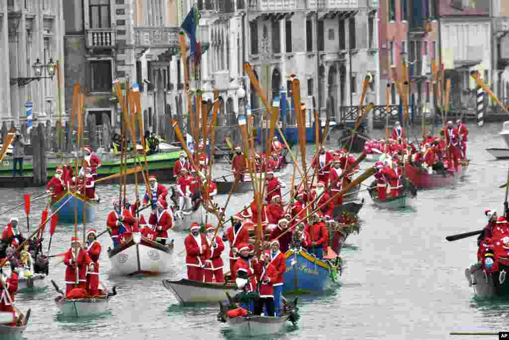 People wearing Santa Claus costumes sail along Venice's Grand Canal aboard traditional Venetians boats, Italy.