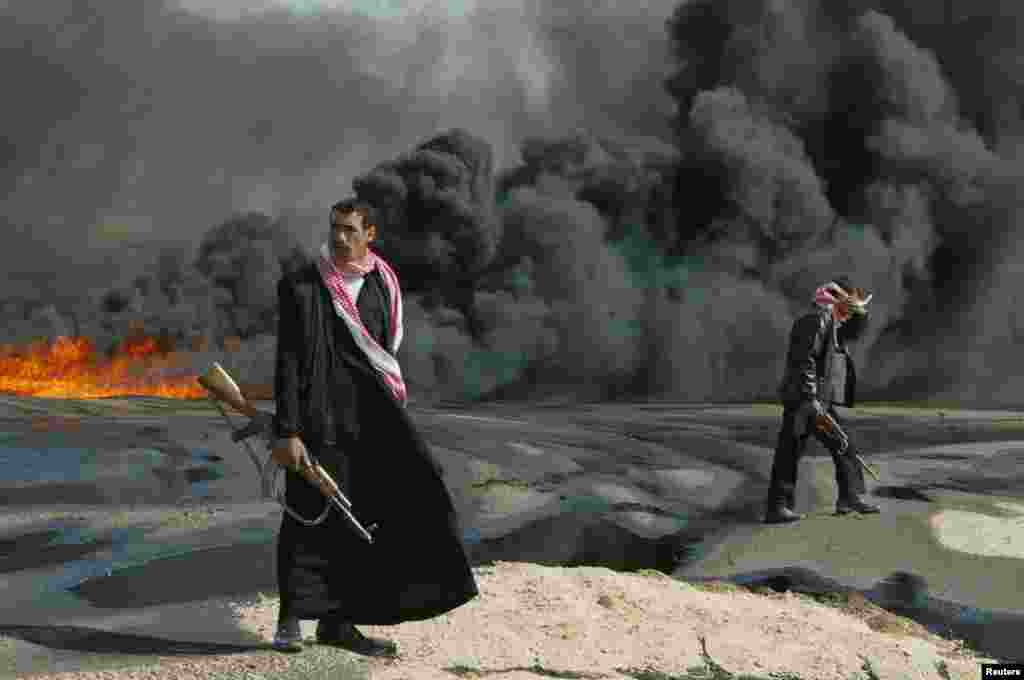 Iraqi policemen guard the burning pipeline near Karbala, Feb. 23, 2004.