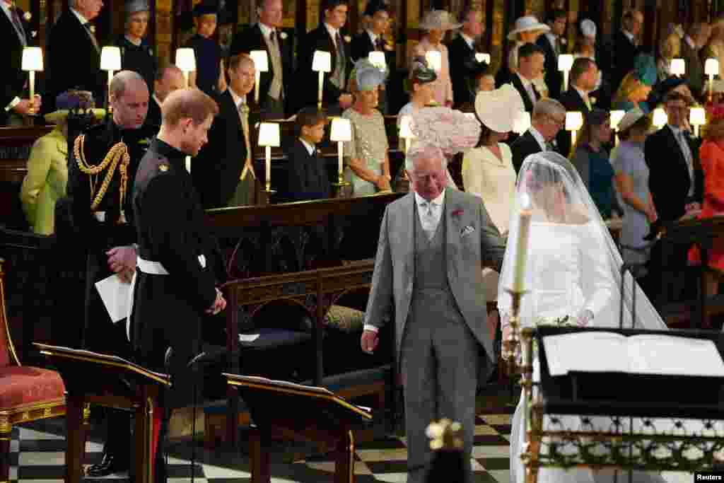 Príncipe Harry olha para a sua noiva, Meghan Markle, que chega acompanhada pelo Príncipe de Gales e pai de Harry, Carlos, na capela de S George, no castelo de Windsor. 19 de Maio 2018.
