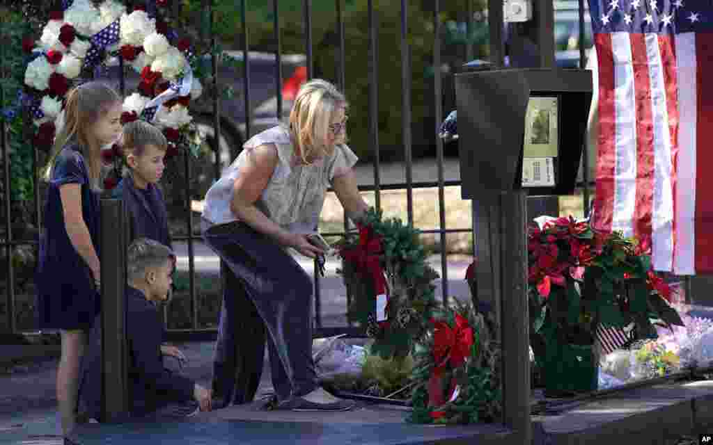Tiffany Utterson, right, and her children, from left to right, Ella, 11, Ian, 10 and Owen, 8, place a wreath outside the gated community entrance to the home of former President George H.W. Bush in Houston, Texas. Bush died late Friday at his Houston home at age 94.