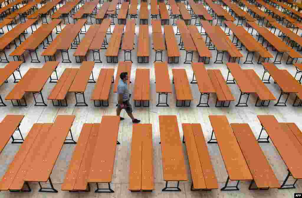 A man walks along empty benches in an Oktoberfest tent prior to the opening of the Oktoberfest beer festival at the Theresienwiese fairgrounds in Munich, southern Germany. The world's biggest beer festival opens on Sept. 17, 2016, and runs until Oct. 3, 2016.