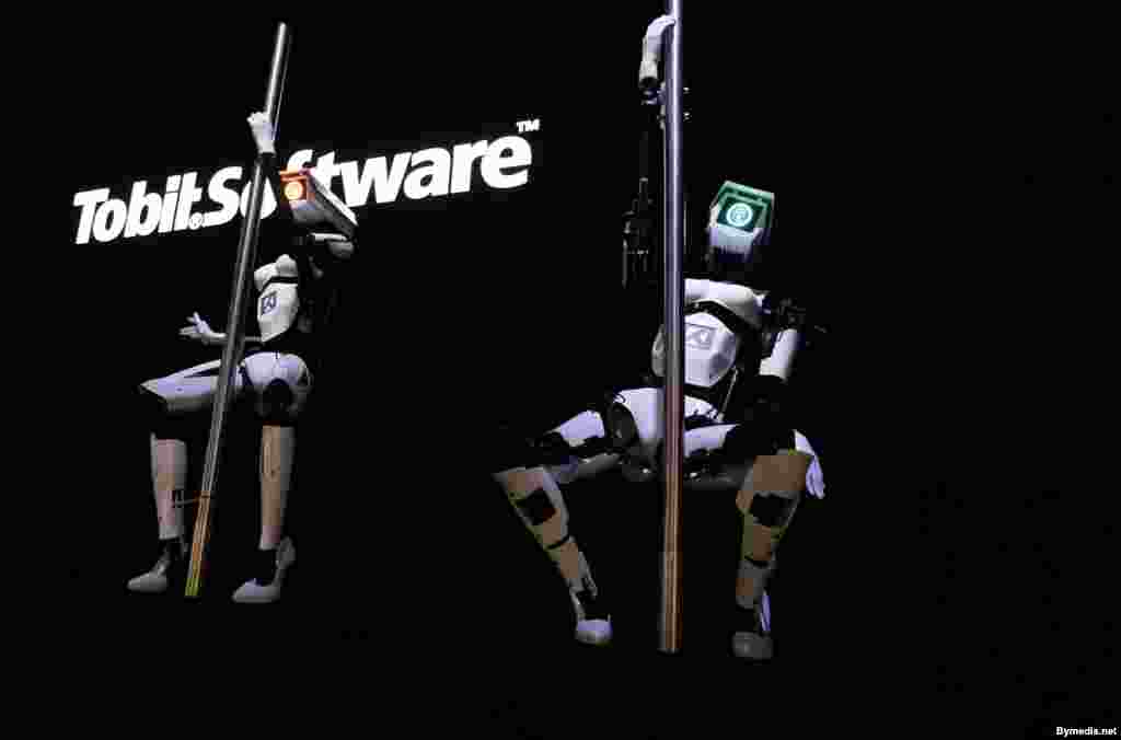 'Female' robots Tessy (L) and Tess (R), wearing white stilletoes, pole dance during a demonstration on the Tobit Software stand at the CeBIT trade fair in Hanover, Germany, Mar. 10, 2014.