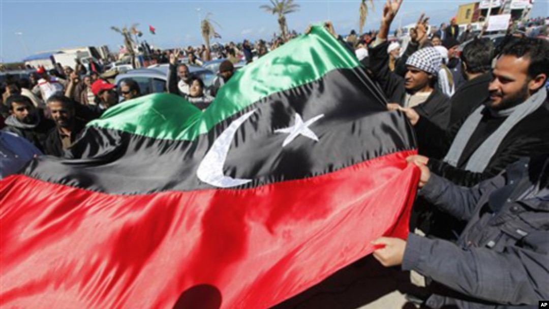 Anti-Libyan leader Moammar Gadhafi protesters wave the old Libyan flag as they celebrate the freedom of the Libyan city of Benghazi, Libya, February 28, 2011