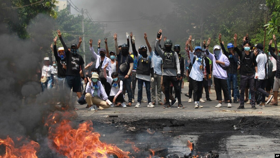 Anti-coup protesters gesture with a three-fingers salute, a symbol of resistance during a demonstration during by police crack down in Thaketa township Yangon, Myanmar, Saturday, March 27, 2021.