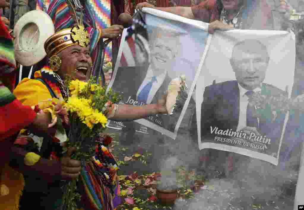 Shamans hold photos of U.S. President Joe Biden and Russia's President Vladimir Putin during a year-end ritual where they predict political and social issues expected to occur in the next year, in Lima, Peru, Dec. 29, 2021.