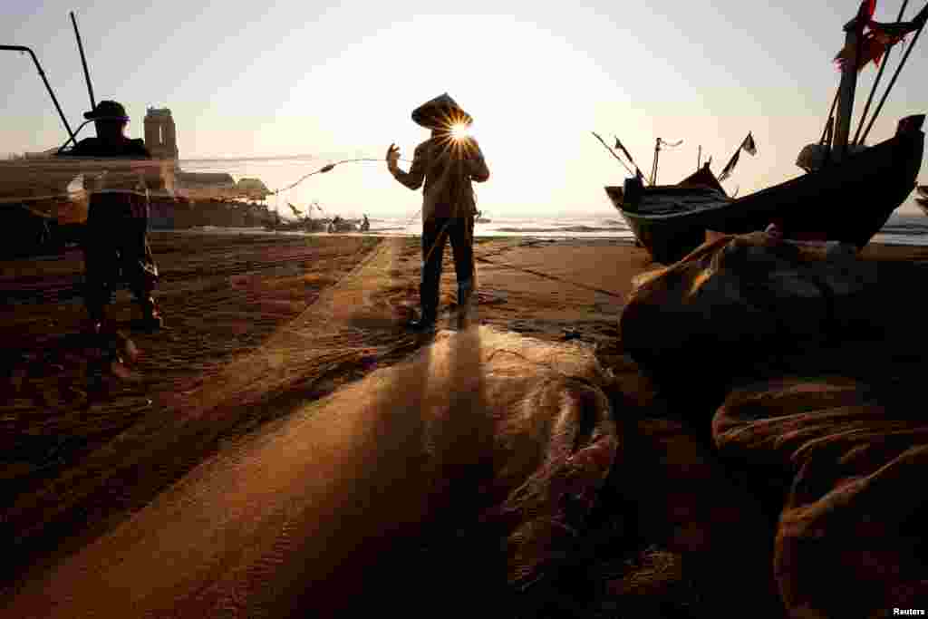 Fishermen clean their nets at a beach in Nam Dinh province, Vietnam.