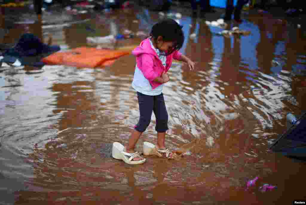 Rosa Julia Romero, a four-year-old migrant girl from Honduras, part of a caravan of thousands from Central America trying to reach the United States, wears her mother's shoes as she walks through a temporary shelter after heavy rainfall in Tijuana, Mexico, Nov. 29, 2018.