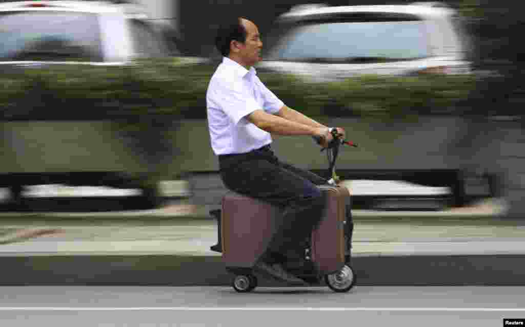 He Liang rides his home-made suitcase vehicle along a street in Changsha, Hunan province, China, May 28, 2014. He spent 10 years modifying the suitcase into a motor-driven vehicle. The suitcase has a top speed of up to 20km/h and the power capacity to travel up to 50-60km after one charge, according to local media.