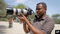 FILE - Somali journalist Mohamed Mohamud holds his camera in the Medina hospital compound in Mogadishu, Somalia, Jan. 18, 2013. Mohamud was killed on the job in 2013.