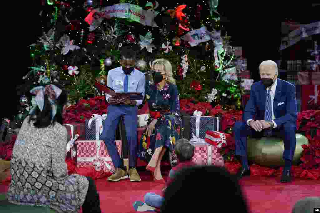 A patient at reads "Olaf's Night Before Christmas" with first lady Jill Biden as President Joe Biden listens at Children's National Hospital in Washington, Dec. 24, 2021.