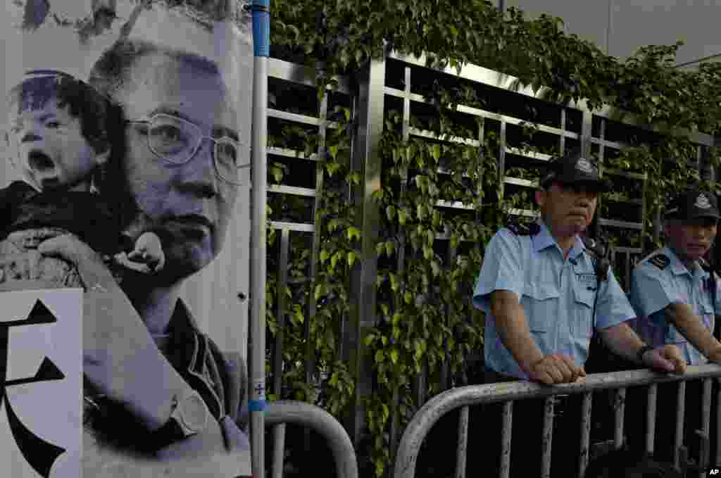 香港中联办外面,警察站岗,旁边是示威者带来的刘霞拍摄的刘晓波照片(2017年7月10日)