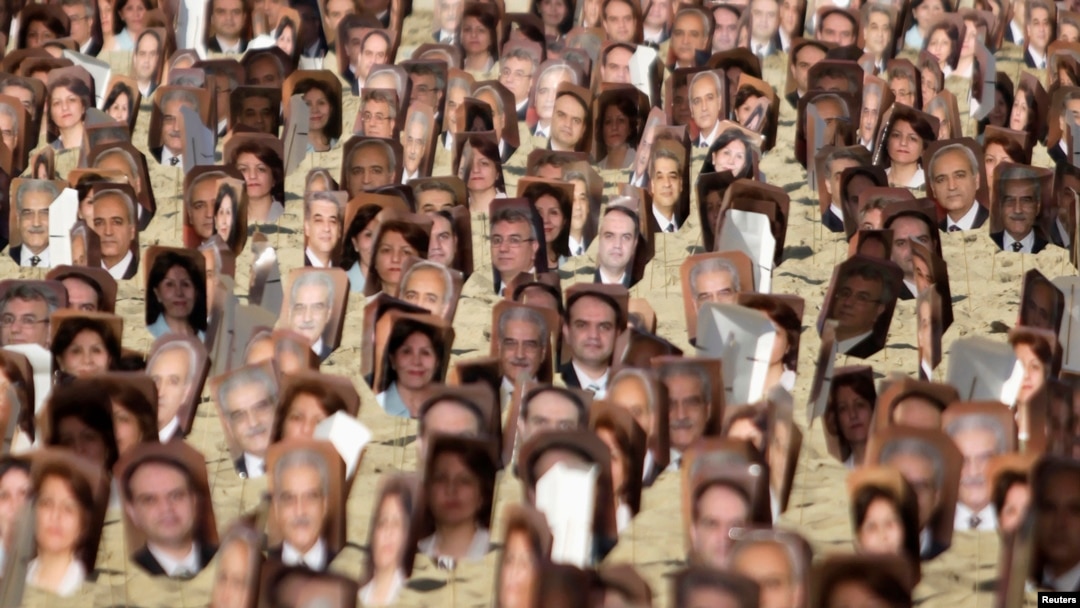 FILE - Multiple pictures of Baha'i religious leaders arrested in Iran are seen during a protest at Copacabana Beach in Rio de Janeiro, June 19, 2011.