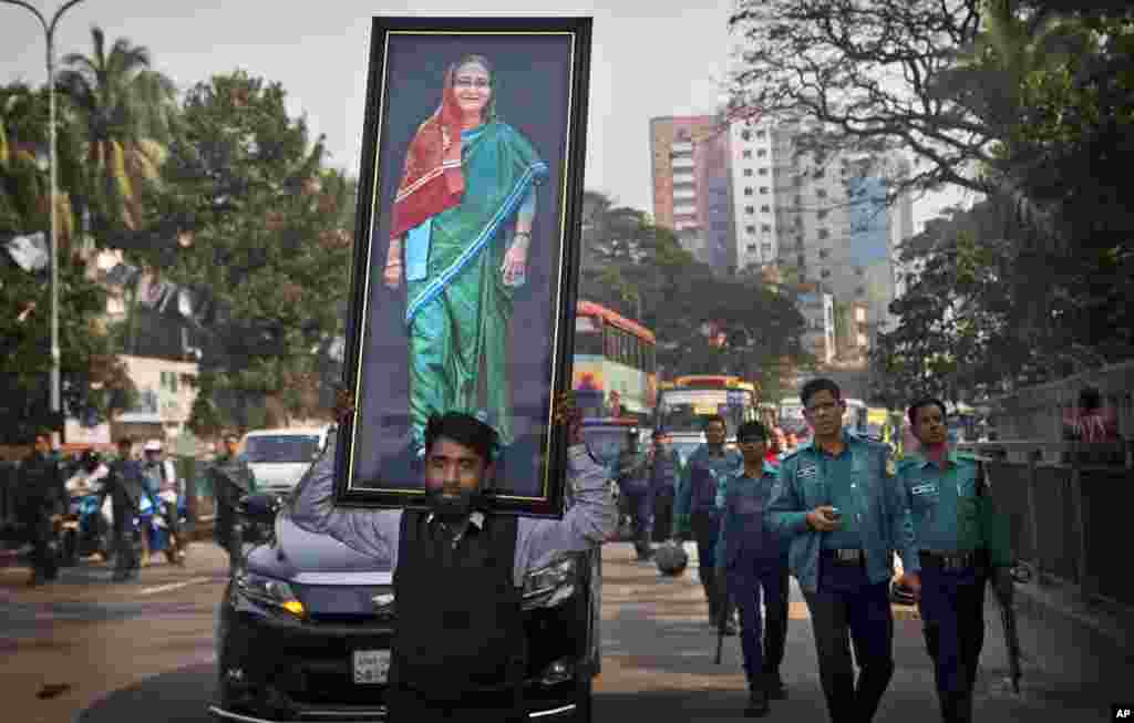 A supporter of Bangladesh Awami League party carries a huge photograph of Prime Minister Sheikh Hasina during an election rally in Dhaka.
