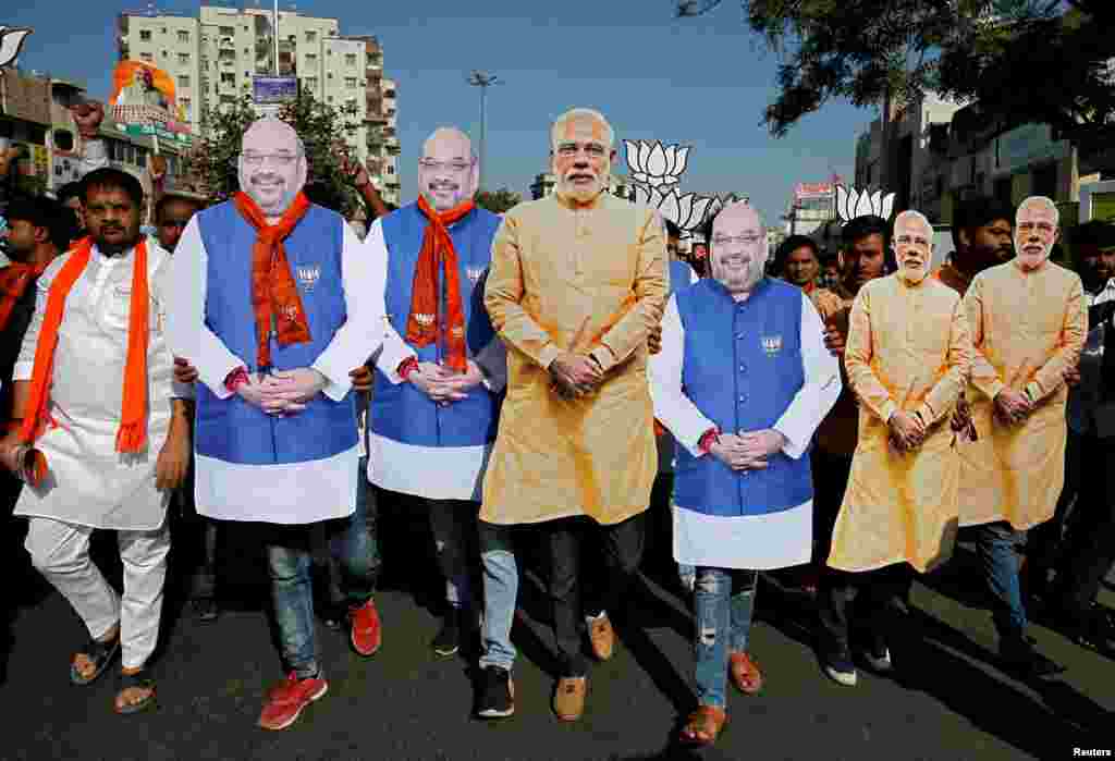 Supporters of India's ruling Bharatiya Janata Party (BJP) wear cut-outs of Prime Minister Narendra Modi and the party president Amit Shah as they walk during an election campaign in Ahmedabad.