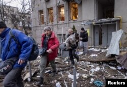 Los residentes locales abandonan el sitio donde los edificios residenciales sufrieron graves daños durante un ataque con misiles rusos, en medio del ataque de Rusia contra Ucrania, en el centro de Kharkiv, Ucrania, el 2 de enero de 2024. REUTERS/Yevhen Titov