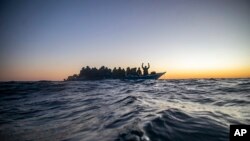Wahamiaji na wakimbizi kutoka nchi mbalimbali za Afrika wakisubiri msaada wakiwa katika boti ya mbao iliyokuwa imesheheni katika Bahari ya Mediterranean maili 122 nje ya pwani ya Libya Feb. 12, 2021. (AP Photo/Bruno Thevenin)