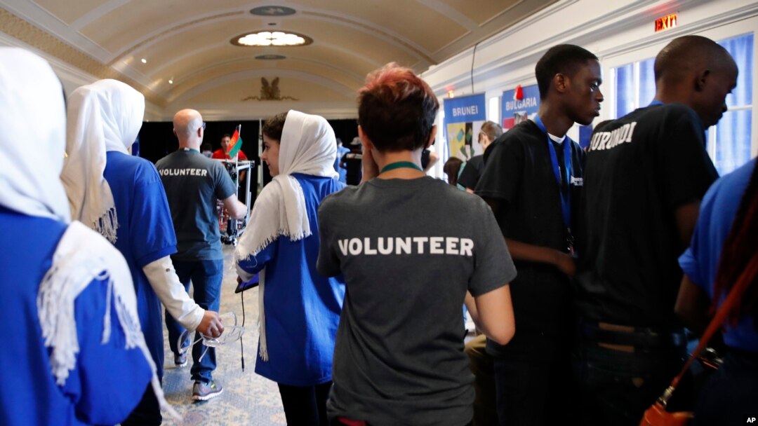 In this July 17, 2017, photo, members of the Afghanistan team, left, walk past two Burundi team members, at right in black shirts, during the FIRST Global Robotics Challenge in Washington.
