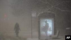 Una mujer camina hacia una parada de autobús en Dr. Martin Luther King Drive en Chicago mientras un hombre espera en la parada durante las horas previas al amanecer del miércoles 2 de febrero de 2022.
