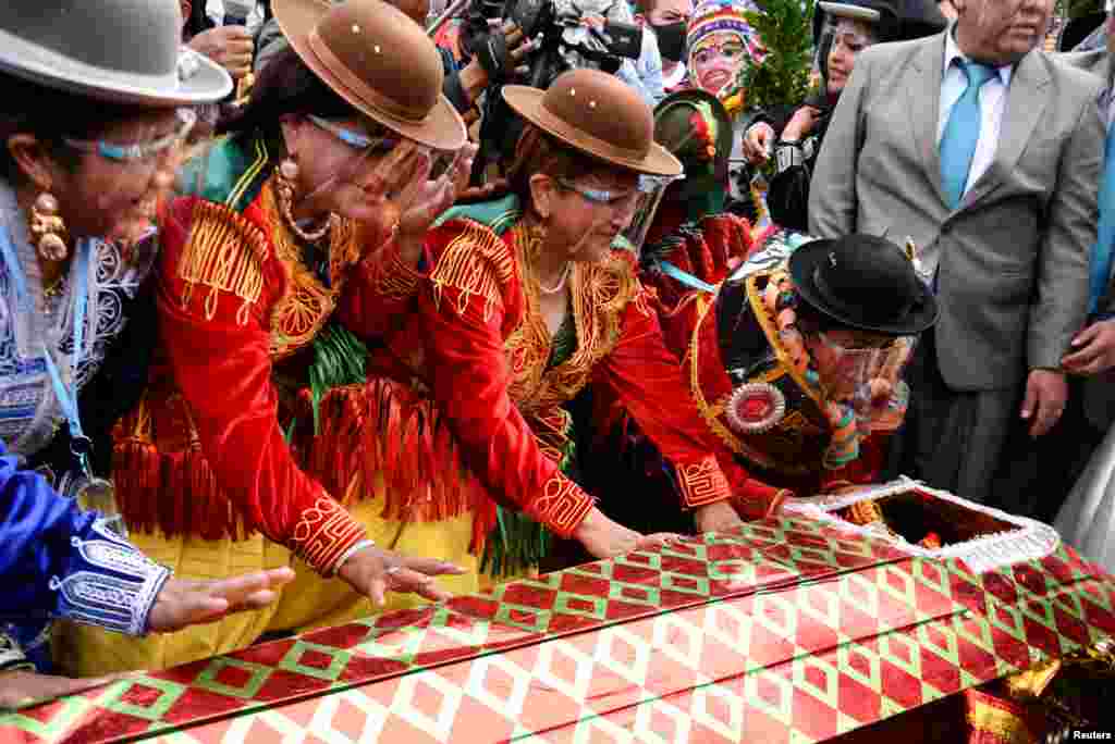 Cholitas, or Andean women, look at a man dressed as "Pepino", a carnival character, before they revive him as part of a ceremony to kick off carnival season in La Paz, Bolivia, Feb. 6, 2022.