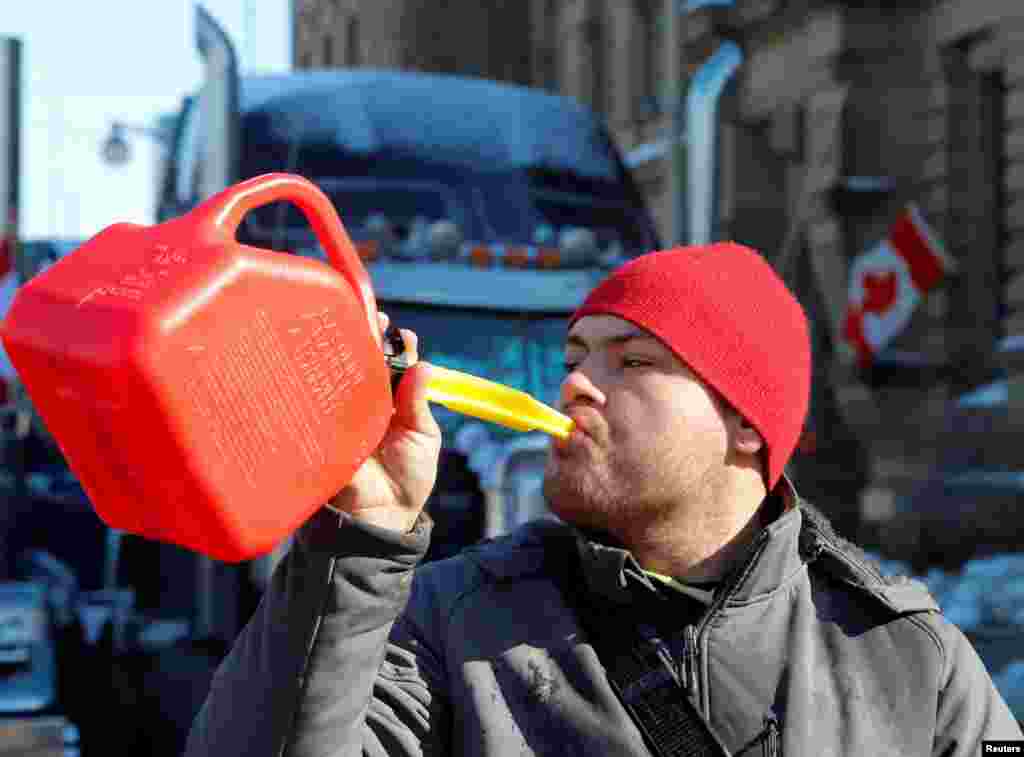 A person pretends to drink from a fuel can after police said they will be targeting the truckers' fuel supply, Feb. 7, 2022. Truckers and their supporters continued to protest COVID-19 vaccine mandates, in Ottawa, Ontario, Canada.