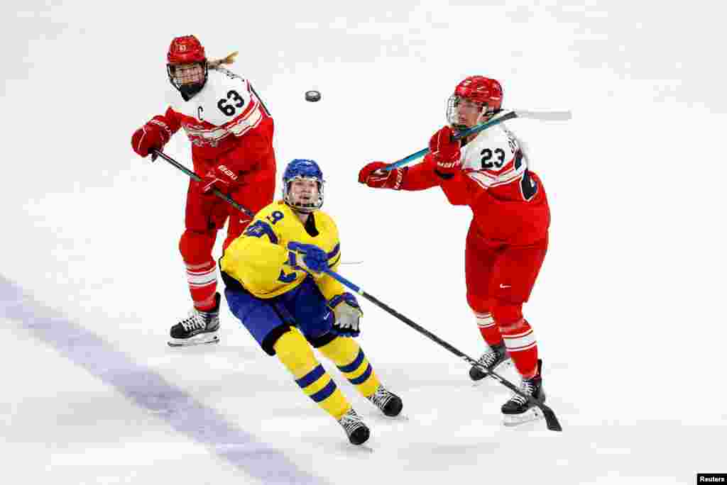 Jessica Adolfsson of Sweden go for the puck with Julie Oksbjerg of Denmark and Josefine Jakobsen of Denmark during the women's preliminary round group B match of 2022 Beijing Olympics ice hockey competition between Sweden and Denmark at the Wukesong Sports Center.