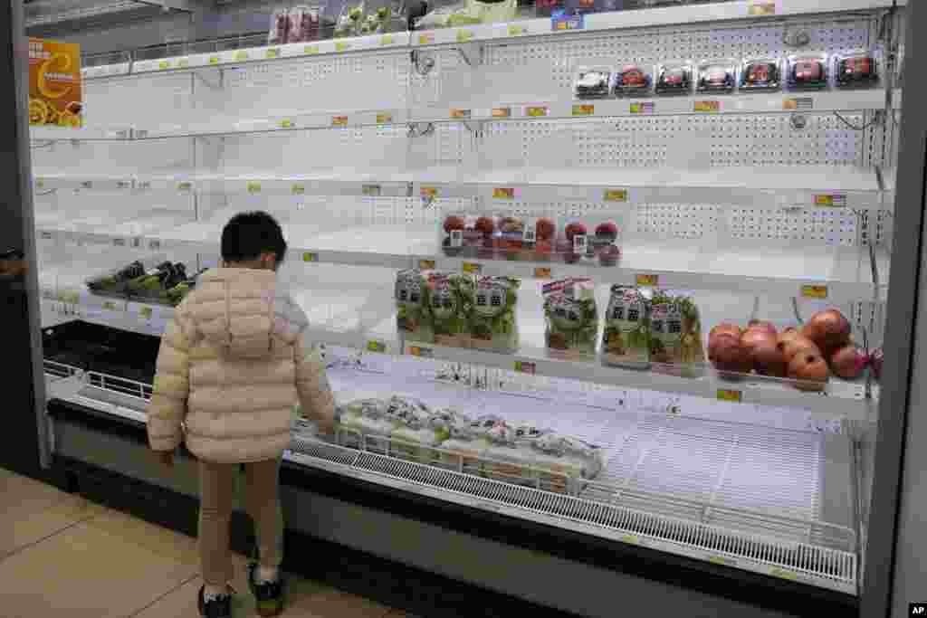 A boy looks at the empty shelves in the vegetable department as residents worry about a shortage of fresh food, at a supermarket in Hong Kong. Hong Kong's leader announced the city's toughest social-distancing restrictions yet, including unprecedented limits on private gatherings, as new daily cases surge above 600.