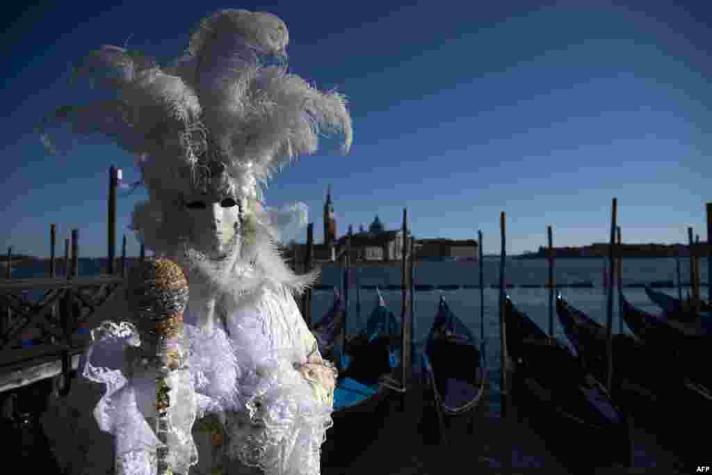 A masked reveler wearing a traditional carnival costume poses in St Mark Square during Venice's Carnival, Italy, Feb. 12, 2022.
