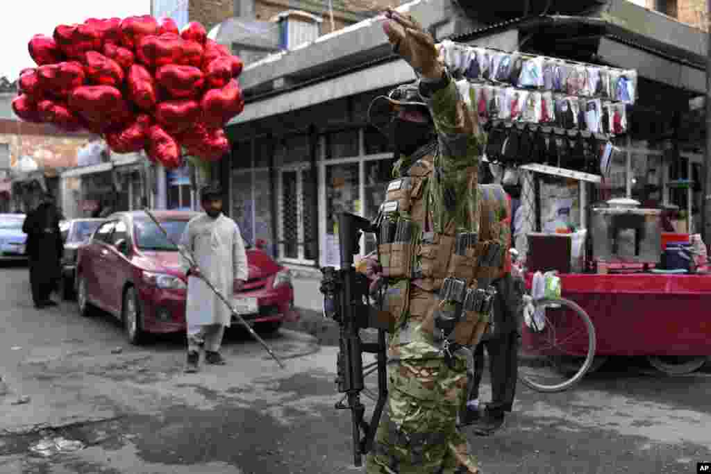 A Taliban fighter directs traffic as a street vendor sells red heart-shaped balloons for Valentine's Day, in Kabul, Afghanistan.