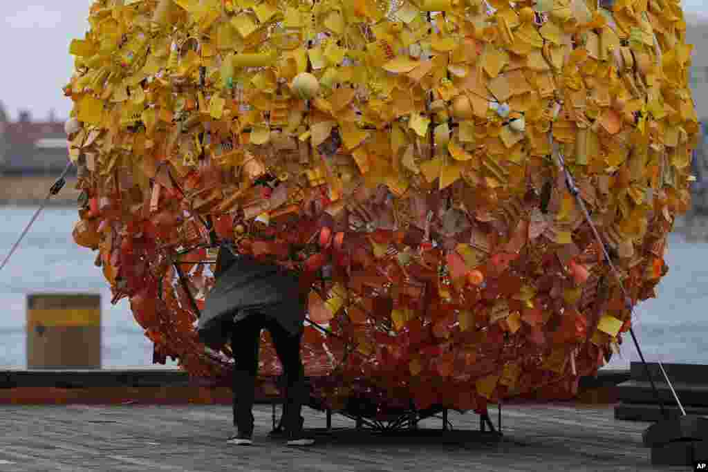 A man looks inside a sculpture made from broken colored plastic artifacts in Copenhagen, Denmark.