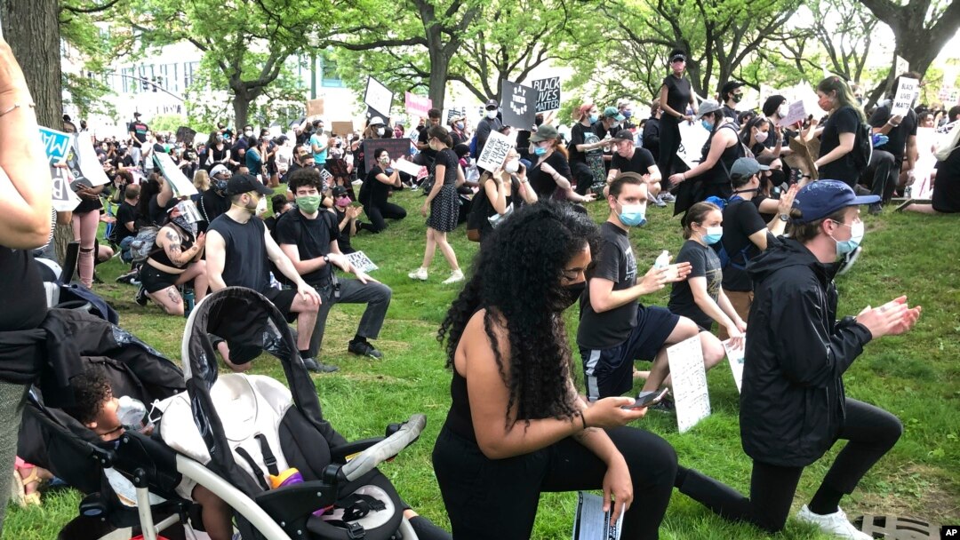 Anjel Newmann, 32, kneels while scanning her phone during a peaceful rally in Providence, R.I. on June 5. 