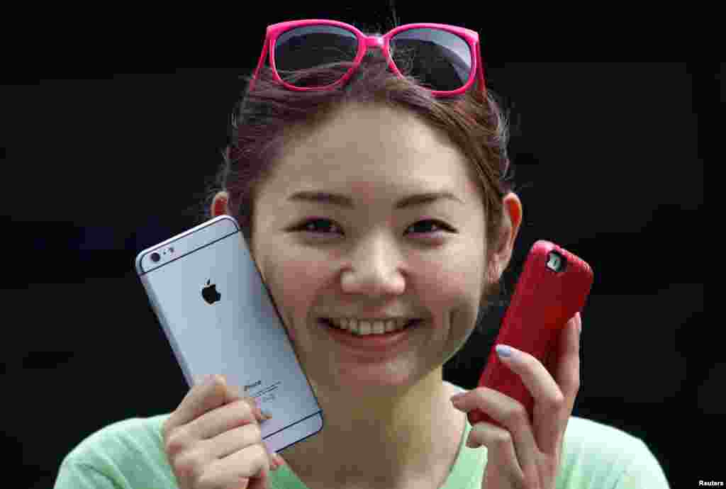A woman holds a mock iPhone 6 plus (L) and an iPhone 5s as she waits in a line, ahead of the September 19 release of iPhone 6 and iPhone 6 Plus, in front of an Apple Store at Tokyo's Ginza shopping district, Japan.