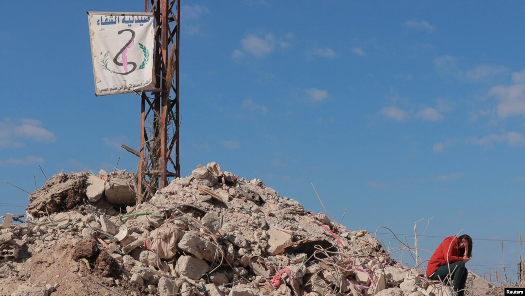 Una mujer se sienta sobre los escombros de lo que fue su casa el 17 de febrero de 2023, en la localidad siria de Jableh, devastada por el mortal terremoto que dejó miles de muertes en Turquía y Siria.